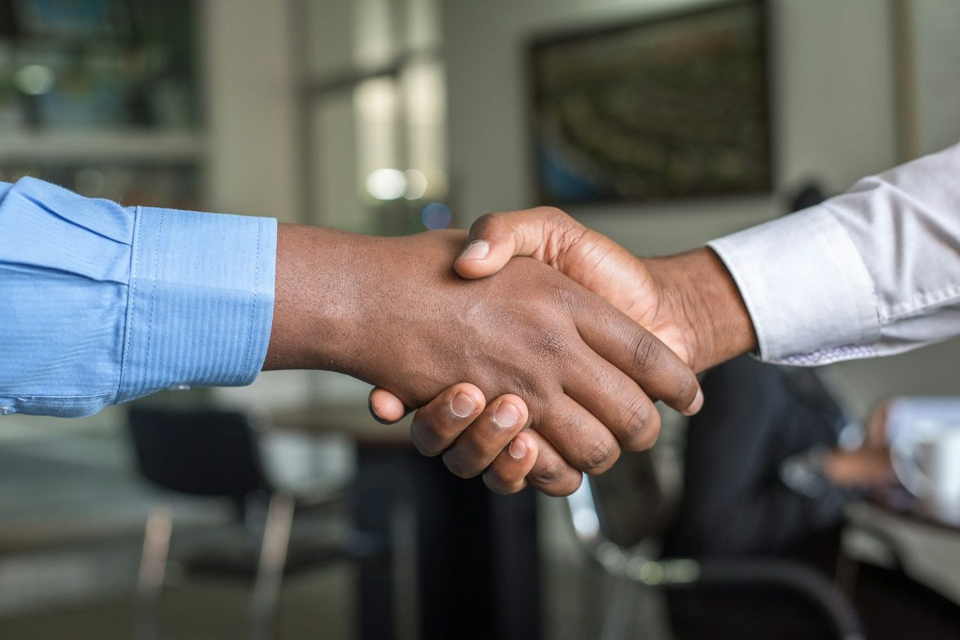 Two professionals shaking hands across a desk in a mentoring meeting